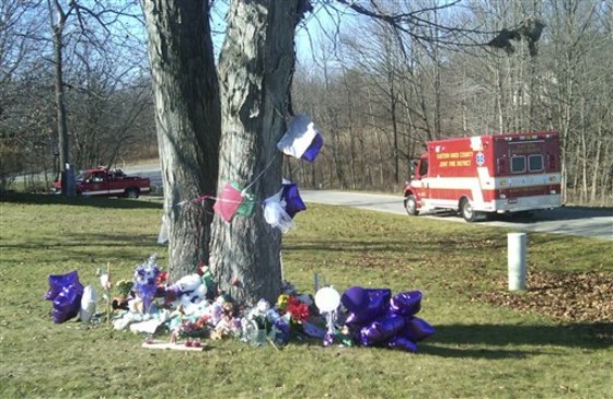 Memorial items surround a tree Tuesday in the front yard of the home in Howard, Ohio, where three people were stabbed. The 13-year-old daughter of one of the victims was rescued, but the bodies of the other three were found days later.
